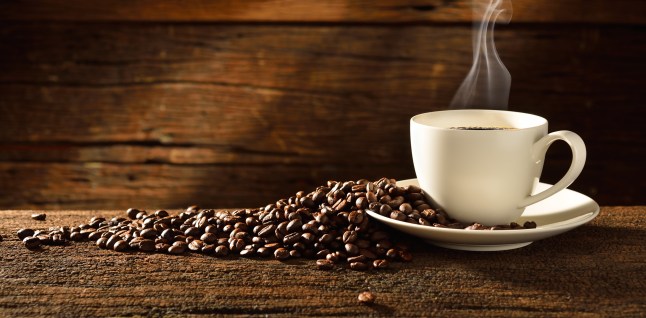 Coffee cup and coffee beans on old wooden background