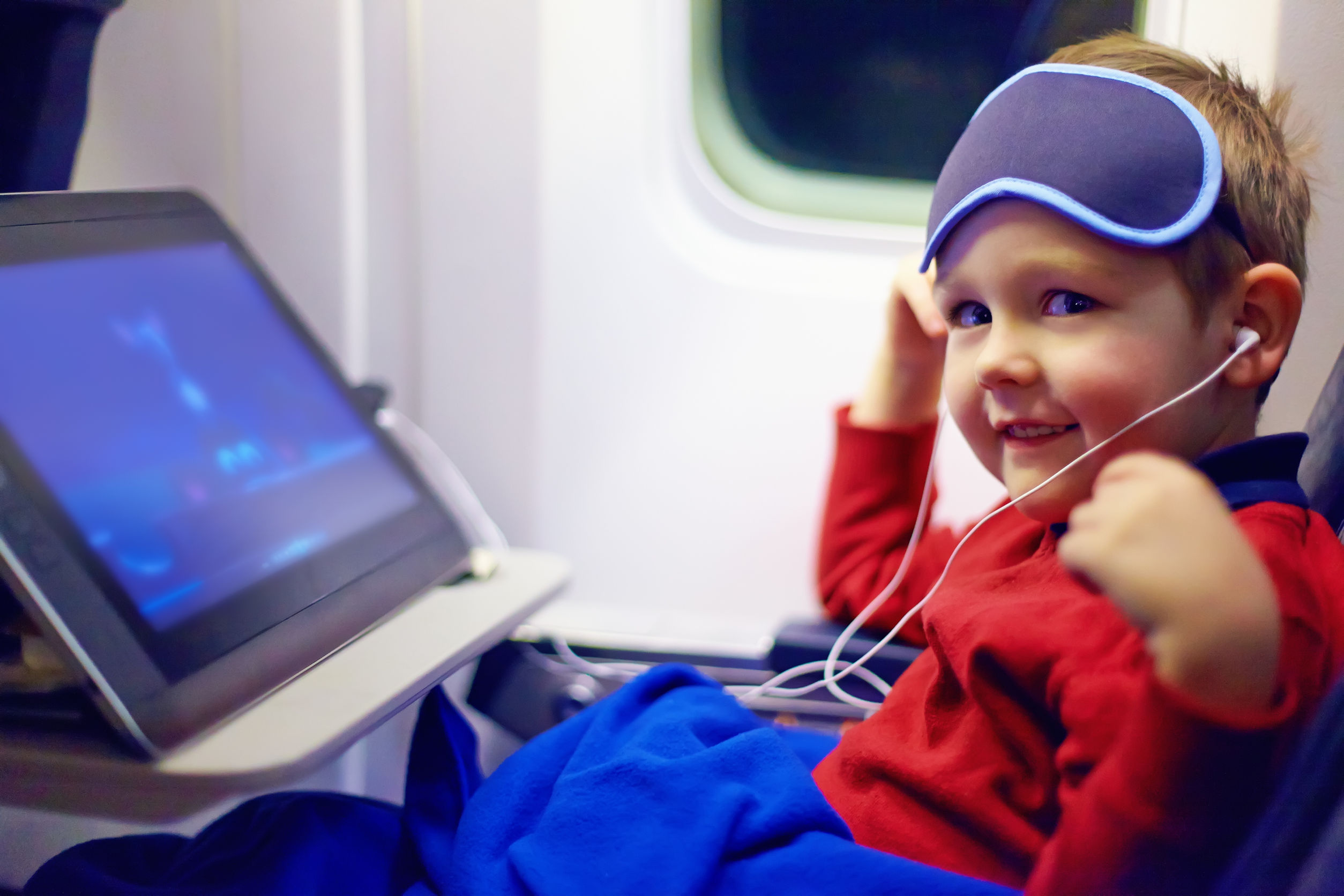 40380868 - cute little kid watching cartoons during the long flight in airplane